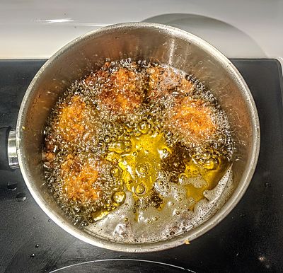 Image of golden brown pakoras frying in hot oil.