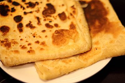 Image of 2 freshly fried paratha on a white plate.